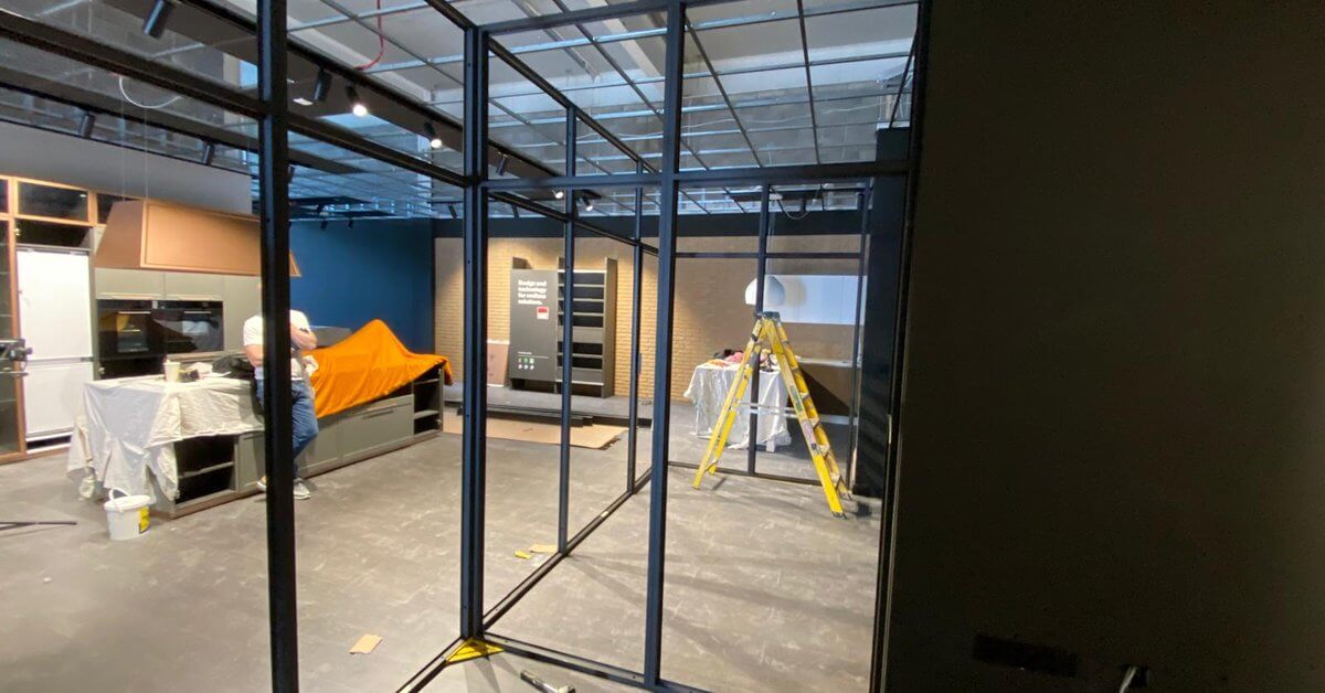 A modern interior space under construction with glass and black metal partitions being installed